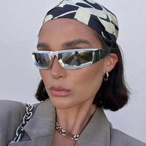 Close-up of Y2K futuristic silver sunglasses and gold chain necklace on a female model
