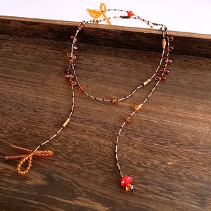 Vintage beaded necklace with amber glass beads and mushroom pendant on wooden tray