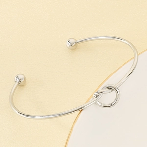 Close-up of silver knot open cuff bracelet with bead ends on minimalist display