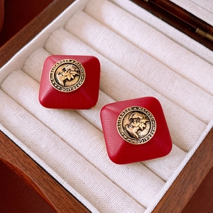 Detail of vintage square red leather earrings with embossed gold Alexander portraits