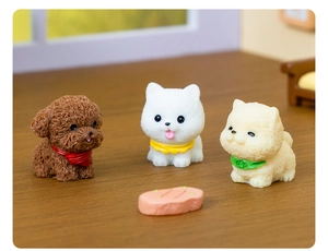 Three cute miniature resin dog figurines with colorful bibs on a wooden desktop