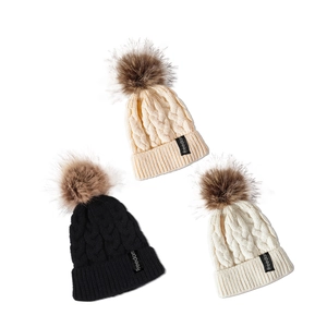 Trois bonnets en tricot noir, beige et blanc avec pompons et étiquettes Freedom
