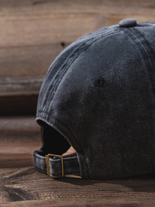 Detailed close-up of adjustable metal buckle and washed fabric on a dark grey baseball cap