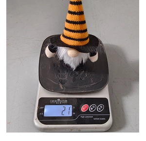 Close-up of a 21g Halloween gnome plush with striped hat on a digital scale