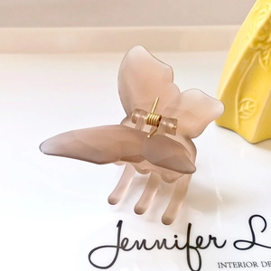 Close-up of matte butterfly hair claw clip with golden metal spring and dusty pink finish