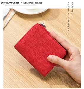 Monedero de cuero rojo con textura de lichi sostenido a mano mostrando tamaño compacto