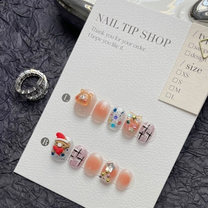 Detail of handmade Christmas bear and tree nail charms on blush pink gradient press-on nails