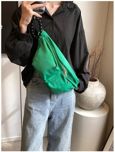 Close-up of green nylon crossbody bag featuring unique black beaded handle and zippers