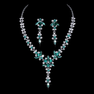 Macro detail of bridal jewelry set with green crystal flowers and silver pear drops