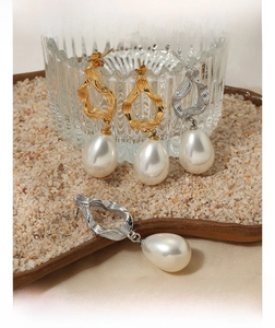 Close-up of elegant textured metal earrings with large pearl pendants in gold and silver
