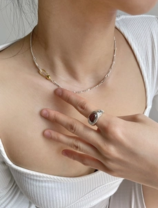 Detail of 925 sterling silver chain necklace and ring with dark red gemstone on model