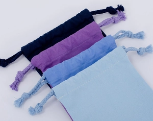 Detail of four cotton drawstring bags in shades of blue and purple on white background