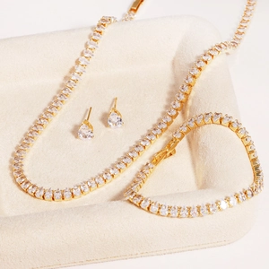 Elegant gold-tone jewelry set featuring pear-cut cubic zirconia necklace, earrings and bracelet