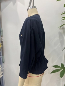Detail view of navy linen safari jacket with gold buttons and cinched waist on mannequin
