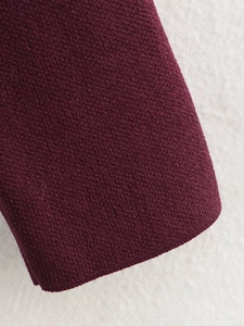 Detailansicht der dunkelroten Stricktextur auf einem weichen weißen Lammfell-Hintergrund