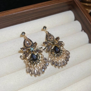 Makroaufnahme von Vintage-Quastenohrringen mit bunten Kristallen in einem Samttablett