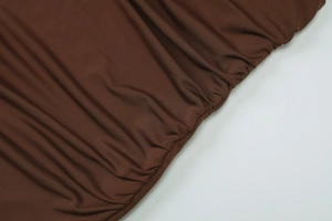Vista macro del tessuto in maglia a coste marrone scuro con trama a pieghe elasticizzata