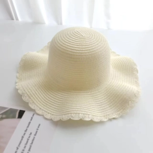 Close-up of cream straw sun hat featuring elegant scalloped edges and woven fiber texture