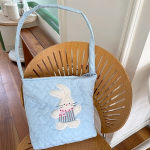 Close-up of light blue quilted corduroy crossbody bag with cute bunny embroidery and heart pattern