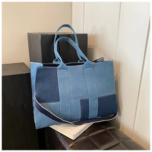 Detail of color-block denim tote bag with blue patchwork fabric and wide shoulder strap