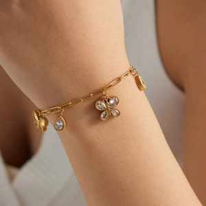 Gold-plated stainless steel bracelet with butterfly and teardrop pendants worn on wrist