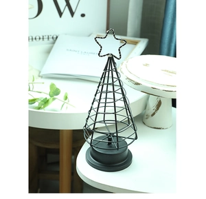 Detail of minimalist black metal wire Christmas tree lamp with star topper and round base