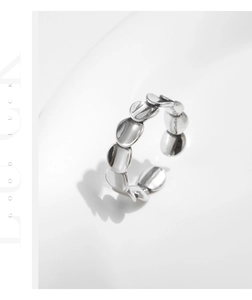 Close-up of overlapping s925 silver scale-shaped discs on an irregular open ring