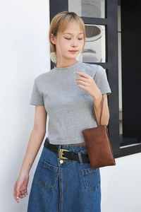 Detail view of a vintage brown leather wristlet bag held by a model in natural light