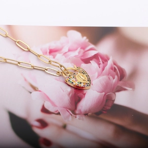 Macro shot of gold paperclip chain necklace with a colorful zircon heart locket pendant