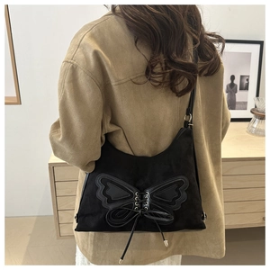 Détail d'un sac porté épaule en daim noir avec motif papillon et lacets sur modèle
