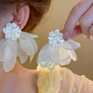 Détail de boucles d'oreilles fleurs en résine avec pétales en tulle et tiges en argent fin