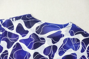 Détail du col rond et du motif géométrique bleu abstrait sur le haut en maille filet