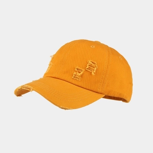 Close-up of bright yellow washed cotton baseball cap with vintage distressed ripped details