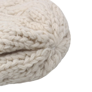 Macro shot of chunky cable knit pattern and top stitching on a cream winter beanie