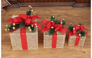 Detailed view of three golden Christmas gift boxes with red ribbons and LED lights