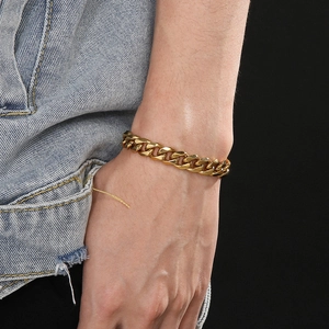 Gros plan d'un bracelet gourmette doré à maillons larges porté au poignet pour le style
