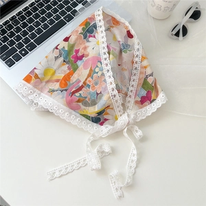 Detailed view of a vintage floral cotton headscarf with delicate white lace trim