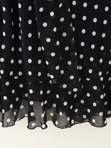 Detail of black polka dot chiffon fabric showing semi-transparent texture and ruffled hem
