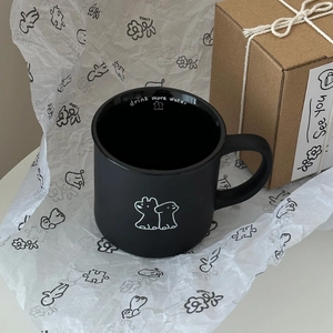 Detail of black ceramic mug with white dog graphic and 'drink more water' text inside