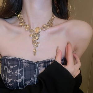 Close-up of golden teardrop necklace with floral crystals and star sparkle effect on model