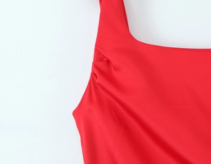 Close-up of red satin dress featuring elegant square neckline and pleated shoulder details