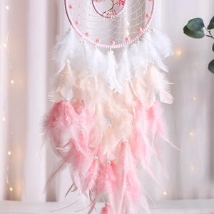 Detail of pink tree of life dreamcatcher with gradient feathers and warm fairy lights