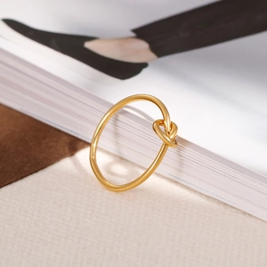 Macro view of gold knot ring design featuring a matte finish and elegant twisted metal style