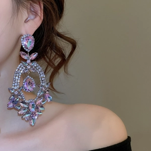 Model wearing large drop earrings featuring purple crystals and silver rhinestones