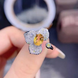 Macro detail of luxury silver flower ring with pave diamonds and yellow center stone