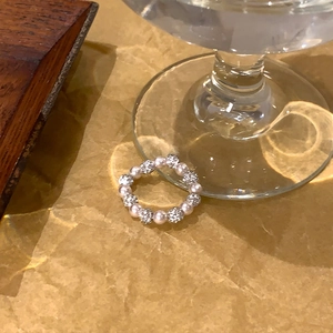 Gros plan d'une bague en perles et boules serties de diamants sur papier texturé