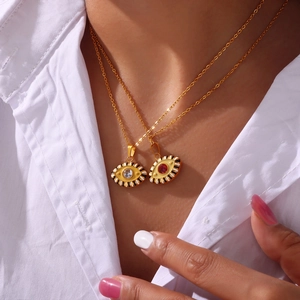 Gold Evil Eye pendant necklace with enamel details and zircons on a female model