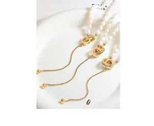 Close-up of pearl necklace with gold double interlocking rings and tassel detail