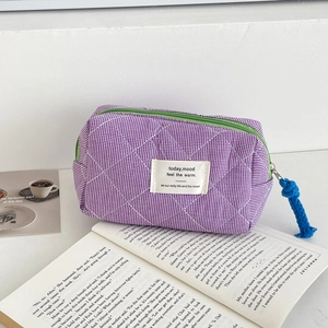 Detail of purple plaid quilted makeup bag with green zipper and woven rope puller