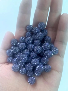 Detail of purple rhinestone disco ball bead held in hand for DIY jewelry making